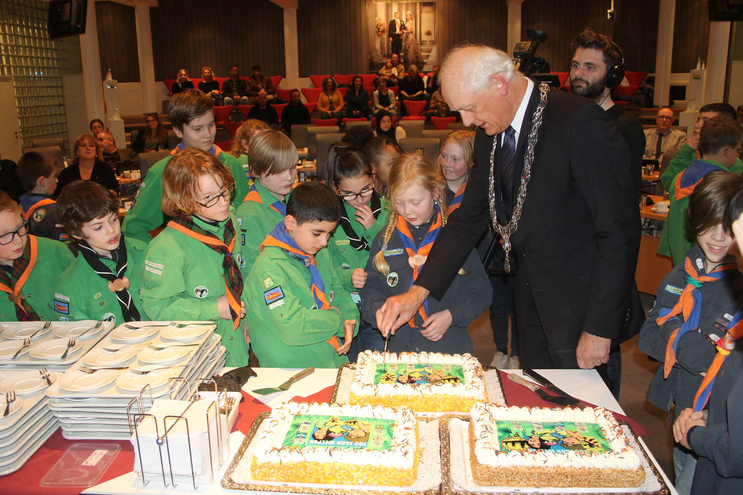 De welpen van Scouting Schiedam bieden taart aan, aan de gemeenteraad van Schiedam om 100 jaar welpen in Nederland te vieren